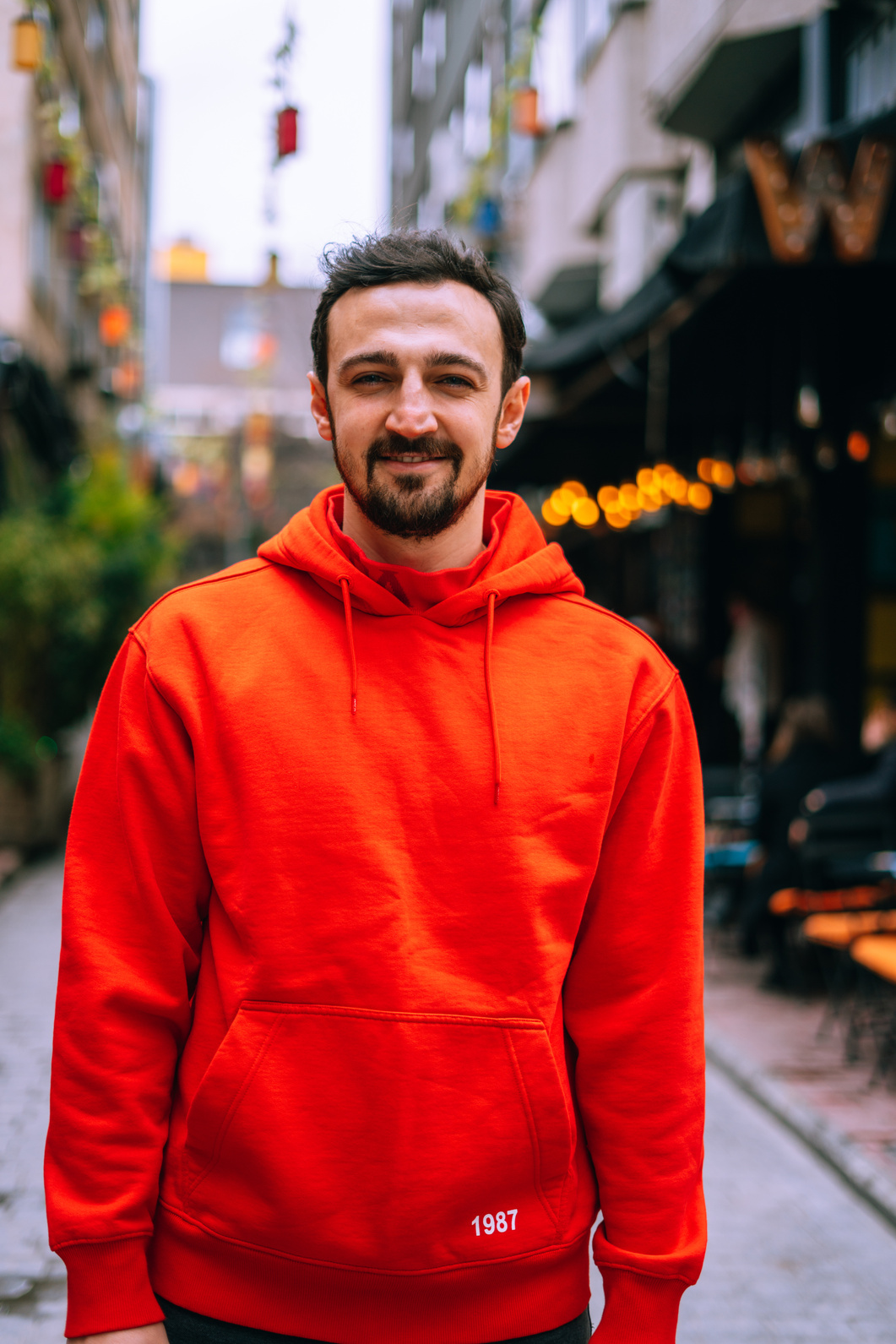 Man in Red Hoodie Standing Near Building