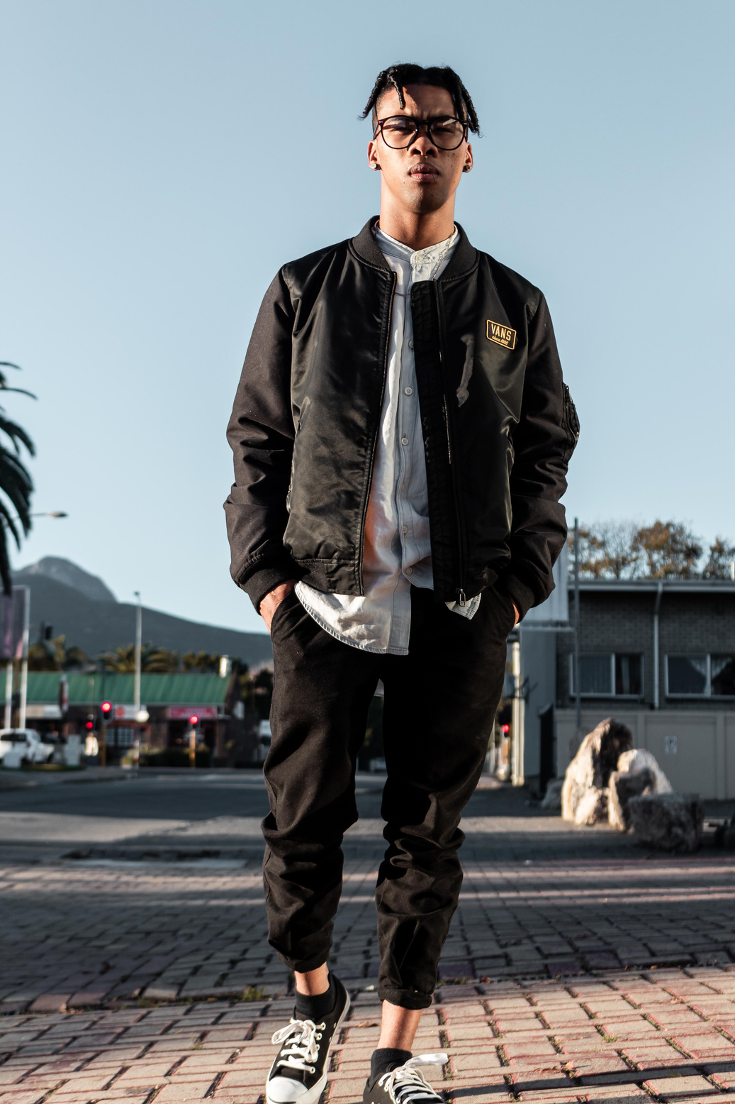 Man wearing black bomber jacket and black trouser posing for a photo