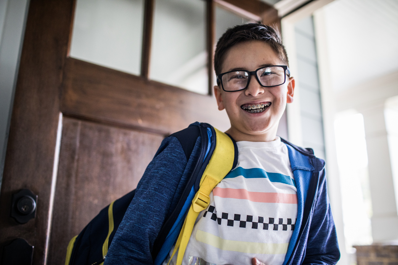 School age boy smiling and leaving for school
